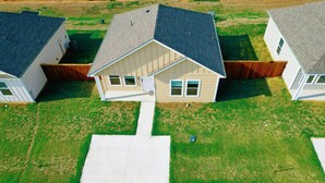 Uma área residencial com três casas, cada uma com um estilo de telhado diferente e um jardim frontal.