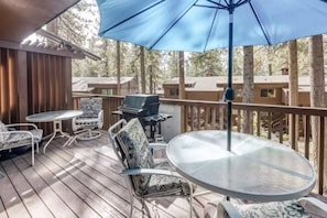 A deck with outdoor furniture, a grill, and a large umbrella.