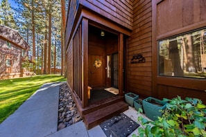 A wooden building with a welcoming entrance, a visible door, and a window overlooking a forested area.