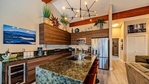 A modern kitchen with a large island, wooden cabinetry, and a built-in oven. - Pinewild Retreat | Sauna, Decks & Beach | Sleeps 6 (Zephyr Cove)