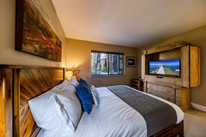 Quarto com cama, televisão, janela com vista e pintura na parede.