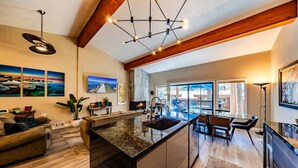 A spacious kitchen with a central island, a dining area with a view, and a living room with a fireplace. - Pinewild Retreat | Sauna, Decks & Beach | Sleeps 6 (Zephyr Cove)