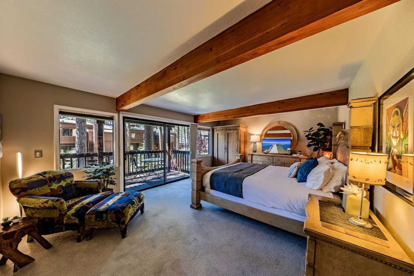 Ein Schlafzimmer mit einem großen Bett, einem Schreibtisch, einem Stuhl und einem Balkon mit Blick nach außen.