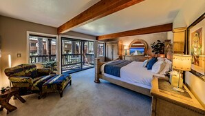 Une chambre dotée d’un grand lit, d’un bureau, d’une chaise et d’un balcon offrant une vue sur l’extérieur.