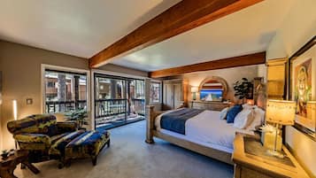 Ein Schlafzimmer mit einem großen Bett, einem Schreibtisch, einem Stuhl und einem Balkon mit Blick nach außen.