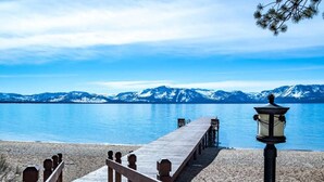 Une jetée en bois qui mène à une plage de sable, avec une montagne en arrière-plan.