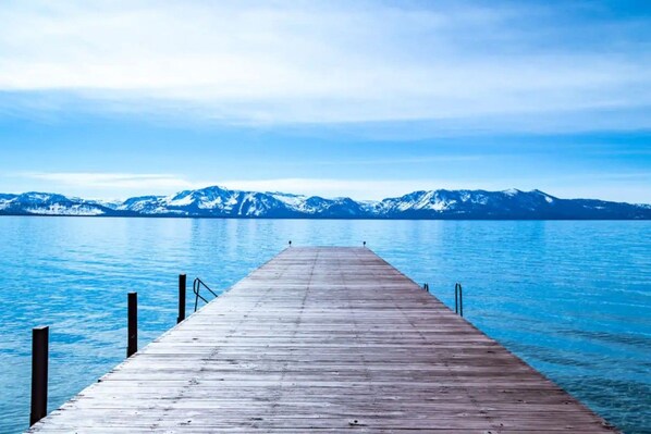 A wooden pier extending into a calm body of water with a mountainous backdrop.