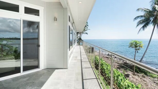 A modern building with large windows overlooking a beach. - Oceanfront Paradise: Breathtaking 3bd/2ba with Panoramic Views of Hilo Bay (Hilo)