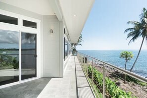 A modern building with large windows overlooking a beach. - Oceanfront Paradise: Breathtaking 3bd/2ba with Panoramic Views of Hilo Bay (Hilo)