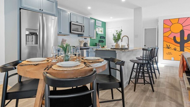A modern kitchen with stainless steel appliances, a central island with seating, and a bright, colorful mural.