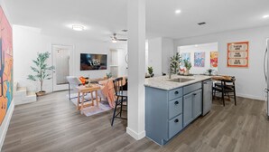 A modern kitchen with a blue island, white walls, and wooden flooring.
