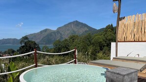 Een hottub op een houten terras met uitzicht op bergen en een meer.
