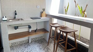 Een moderne keuken met een ingebouwde gootsteen, houten barkrukken en een raam met planten.