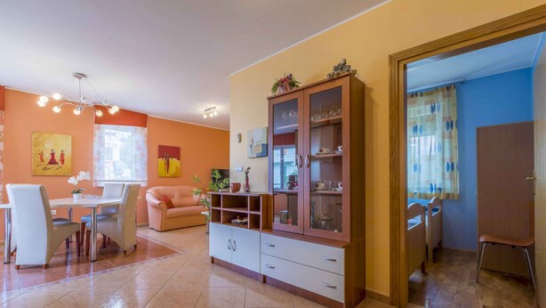 A dining area with a table and chairs, a cabinet with glass doors, and a sofa. - Holiday apartment with air conditioning and Internet access (Dramalj)