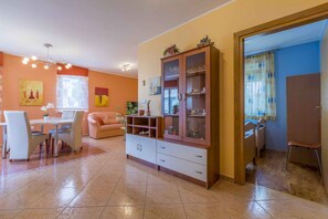 A dining area with a table and chairs, a cabinet with glass doors, and a sofa. - Holiday apartment with air conditioning and Internet access (Dramalj)