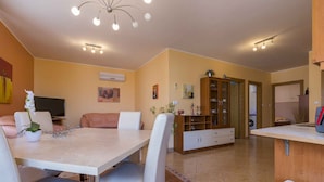 A modern kitchen with a dining area, featuring a large island, white cabinetry, and a central light fixture. - Holiday apartment with air conditioning and Internet access (Dramalj)