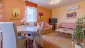 A living room with a dining table, two sofas, a TV, and a potted plant. - Holiday apartment with air conditioning and Internet access (Dramalj)