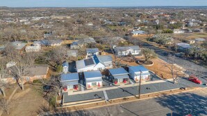 An aerial view of a residential area with multiple houses, a parking lot, and a clear sky. - Pop 1: Hot-tub + Close to Main St (Fredericksburg)
