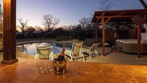 Un área junto a la piscina con una pérgola, sillones de descanso y un jacuzzi.