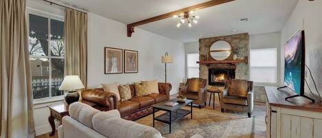 Una sala de estar acogedora con chimenea, sofá de cuero y una mesa de centro.