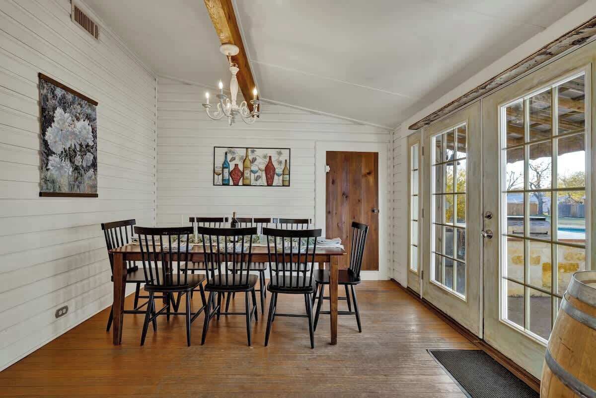 A dining area with a wooden table and chairs, a chandelier, and artwork on the walls.