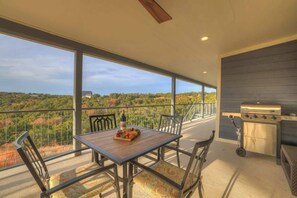 A balcony with a table set for dining, a grill, and a view of a natural landscape. - Esperanza Ranch W/hot-tub, Fire Pit, Gorgeous View (Fredericksburg)