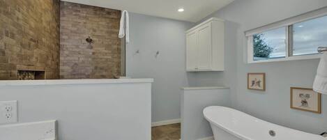 A modern bathroom with a freestanding bathtub, a wooden accent wall, and a window providing natural light.