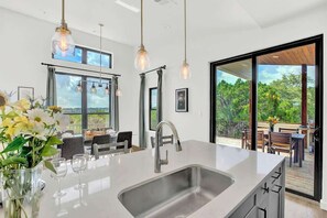 A modern kitchen with a large island, stainless steel sink, and pendant lighting. - Luxury Lakeview Home w/ Pool & Beach Access! - Not Active (Leander)