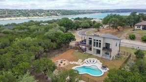A modern house with a swimming pool, surrounded by trees and a view of the sea. - Luxury Lakeview Home w/ Pool & Beach Access! - Not Active (Leander)