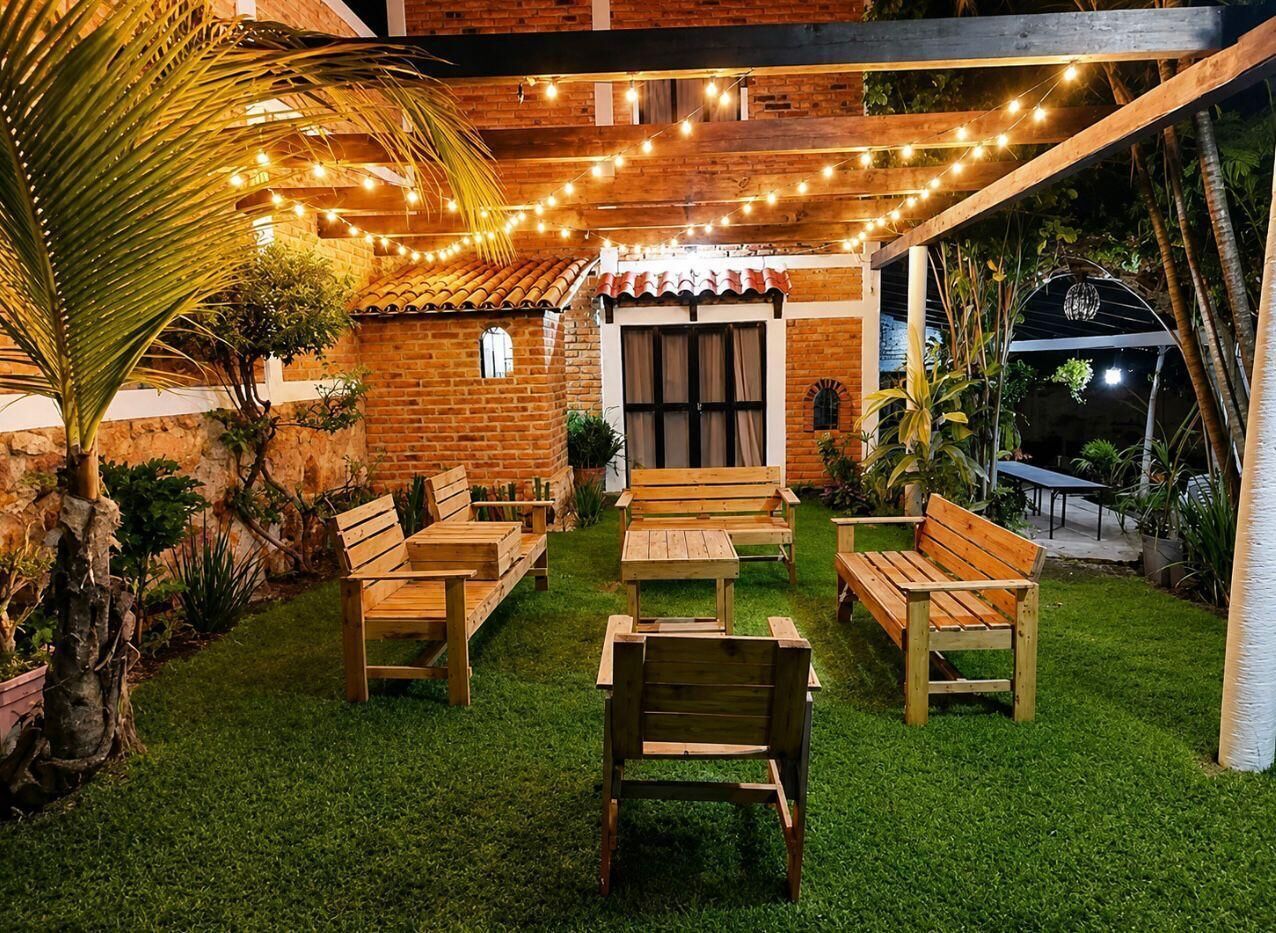 An outdoor patio with wooden furniture, string lights, and a brick wall.
