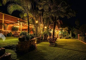 A well-lit outdoor area with a wooden bench, stone planter, and a brick building. - Cool cabin with a view, 5 minutes from downtown Tequila, Jalisco (Tequila)