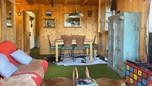 A rustic cabin interior with a dining area, wooden walls, and a colorful cabinet. - The apartment is in a small 3-storey residence and is ideally located in a quiet area just above the (Gryon)