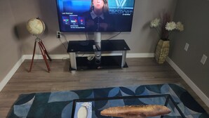 Un televisor de pantalla plana sobre un soporte, un globo terráqueo, un florero con flores y un cuadro en una mesa de centro.