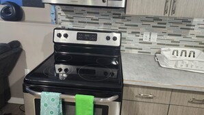 Una cocina con estufa negra, microondas arriba y salpicadero de azulejos.