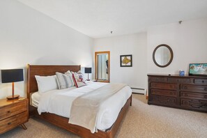 Une chambre à coucher avec un lit en bois, une table de chevet avec une lampe, une commode et un miroir au mur.