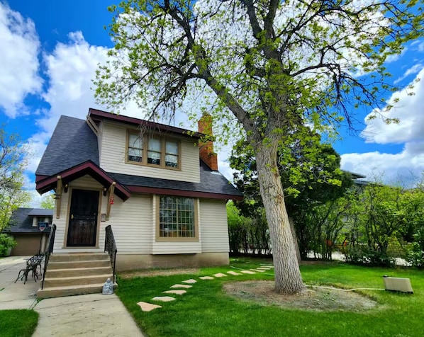 A two-story house with a front porch, a chimney, and a tree in the yard. - The Quad Haven & Loft (Casper)