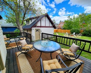 A deck with outdoor furniture, a glass table, and a view of a house in the background. - The Quad Haven & Loft (Casper)