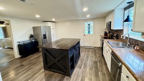 Una cucina moderna con isola centrale, elettrodomestici integrati e un'ampia finestra.