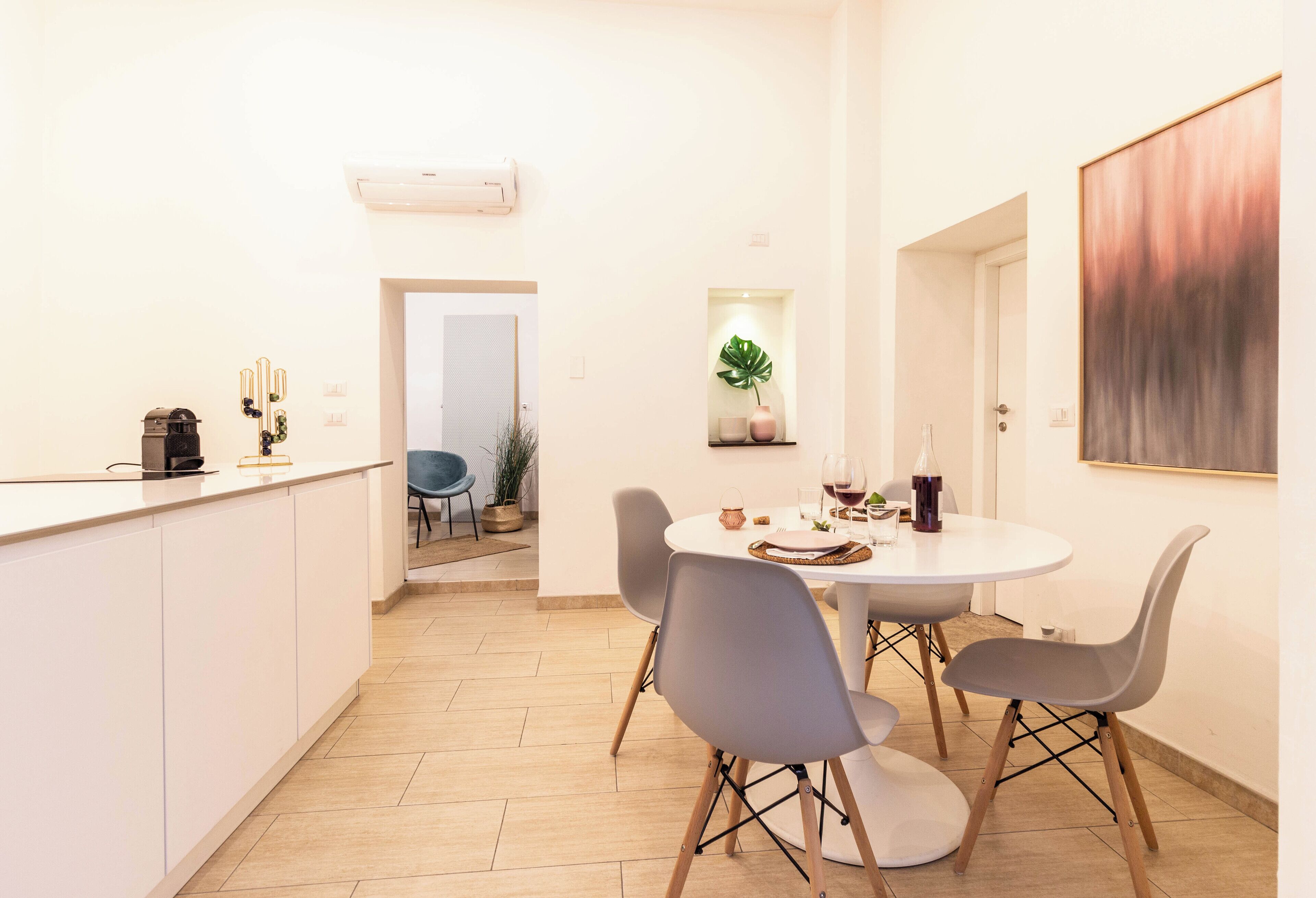 Une cuisine moderne avec un coin repas, comprenant un plan de travail blanc, des chaises grises et une table ronde.