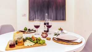 A dining table set with a cheese platter, fruits, wine glasses, and a bottle of wine. - Dama Sicilian Luxury Home & SPA elegance and relaxation between Etna Catania and Taormina (Giarre)