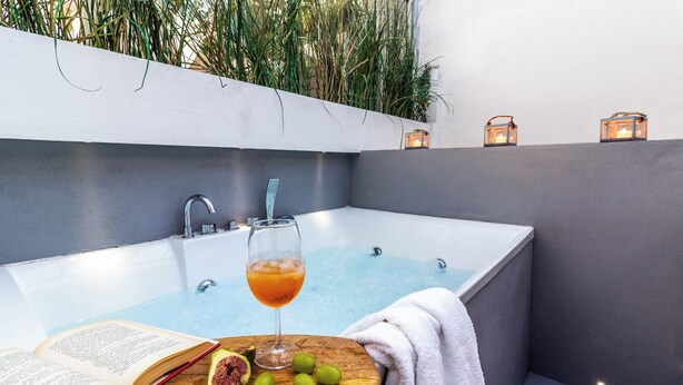 A modern bathroom with a bathtub, a wooden side table with a book, a glass of drink, and fresh fruit. - Dama Sicilian Luxury Home & SPA elegance and relaxation between Etna Catania and Taormina (Giarre)