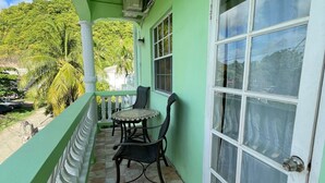 A balcony with a tiled floor, a table with chairs, and a large window with curtains.
