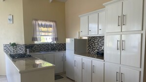 A compact kitchen with white cabinets, a tiled backsplash, and a central island.