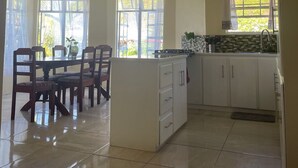 A spacious kitchen with a dining area, featuring a large island, white cabinetry, and a tiled floor. - Hibiscus Apartment Lovely 2-bedroom apartment with AC in Gros Islet/Corinth (Gros Islet)