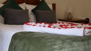 A neatly made bed with white linens, green and gray pillows, and red rose petals. - Charming retreat in Machico - 5 min Beach and B Center (Machico)