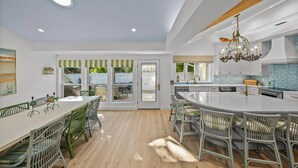 Una cocina moderna con una isla grande, piso de madera y vistas al exterior.