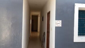 A narrow hallway with a white door on the right and a window with a grid pattern on the wall. - En la 96 (Cancún)