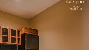 A dining area with a round table, two chairs, a black refrigerator, wooden cabinets, and a coffee maker. - JUNAB HOUSE - APARTMENT 4 (El Cuyo)