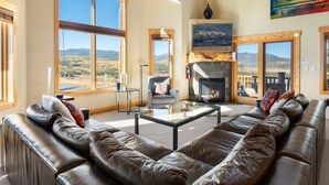 A spacious living room with leather sofas, a glass coffee table, and large windows offering mountain views. - Spruce Ride Villa 714-H I Great Views I Bunk Room I Gas Fire Table I Discounted Attractions (Fraser)