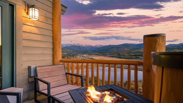 A wooden deck with a fire pit, a bench, and a view of mountains and a lake. - Spruce Ride Villa 714-H I Great Views I Bunk Room I Gas Fire Table I Discounted Attractions (Fraser)